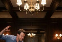 He slapped me in front of his entire family, the sound snapping through the dining room like a gunshot. “I’m the man of this house,” my husband hissed, daring me to cry. His mother smirked. His brothers laughed. I swallowed the sting and whispered, “Then act like one… because you just signed your eviction.” Five minutes later, the front door opened—and every smile in that room died.