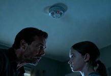 “I stood on the chair, heart hammering against my ribs. I wasn’t looking at a battery; I was staring into a tiny, glass lens hidden inside the smoke detector. ‘They’re watching me,’ I whispered, my skin crawling. I didn’t rip it out. I played along. Three days of deafening silence passed until my daughter leaned in, smiling coldly: ‘Dad, why were you crying in your sleep last night?’ I never told a soul. How did she see me?”