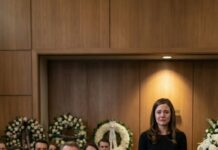 At my husband’s funeral, his mother looked straight at me and said coldly, “Better he’s gone now than forced to live with the embarrassment she brought him.” A few relatives nodded, whispering their approval. Before I could respond, my eight-year-old son rose from his seat, gripping his dad’s phone with both hands. “Grandma,” he said in a steady voice, “do you want me to play the recording Dad made about you last week?” Her expression collapsed instantly—the color drained from her face as the entire room fell silent.