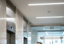 I showed up at my wife’s office to surprise her—CEO suite, glass walls, “AUTHORIZED PERSONNEL ONLY” glaring above the door. I smiled at the guard. “I’m the CEO’s husband.” He burst out laughing. “Sir, I see her husband every day… and he’s walking out right now.” My stomach dropped as a man in a tailored suit stepped into the lobby. I forced a grin. “Oh… that’s me.” Then he turned and called her name.