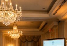 At our wedding, I watched my husband lift his glass and smile like he owned the room. “This dance,” he announced, “is for the woman I’ve loved for ten years.” My heart surged—until he walked past me… and stopped in front of my sister. The crowd erupted, clapping like it was romantic. I tasted blood where I bit my lip, then said one sentence into the microphone. His face drained. His knees buckled. And the music didn’t stop.