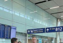 I watched my husband glide through the terminal like a man with nothing to hide—new watch, smug smile, my credit cards burning in his pocket. “Relax,” he whispered to her, “it’s all taken care of.” All taken care of… with $850,000 stolen in my name. Then the loudspeaker crackled: “Mr. ___, please step aside. Customs needs to speak with you.” His face drained. She froze. And I? I stepped closer, phone recording—because he still didn’t know I’d arrived first… and I wasn’t alone.