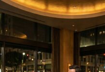 I clutched my daughter’s tiny hand as we stepped into that glittering Los Angeles restaurant, our stomachs screaming louder than the soft jazz. The waiter glanced at my torn shoes and sneered, “People like you don’t belong here. Get out.” When he reached to shove me, a calm voice cut through the room like a blade: “Touch her—and you’re done.” A young billionaire in the corner stood up, draped his coat over my shoulders, and said, “Serve them your best. They’re my guests.” I whispered, shaking, “Why would you help us?” His eyes hardened. “Because I used to be invisible too.” Then he faced the room: “While you waste food, children pray just to survive tonight.” And as my daughter took her first bite, I realized… this wasn’t the ending. It was the beginning of something that would expose everyone in that room.