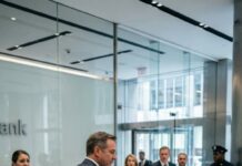 She walked into a Manhattan bank with a $50,000 check, expecting a simple withdrawal—until the teller smirked, “This isn’t a shelter.” When she pleaded, “Please, just verify it,” the manager stepped in, voice sharp: “Get out, beggar.” Then—SMACK—his hand struck her face, and the entire lobby went silent as she collapsed to the marble floor. She left shaking… and made one phone call that would change everything.