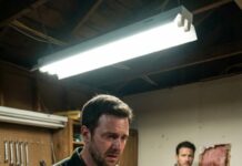 A year after my wife died, I hired an electrician to rewire her old workshop. Midday, he called, voice low: “Sir… you need to come home. Now. I found something hidden inside the wall—but come alone.” My stomach turned. When I arrived, the workshop smelled like dust and memories. He pointed to a fresh opening in the drywall and whispered, “This isn’t an accident.” I looked inside… and my grief suddenly felt like a lie.